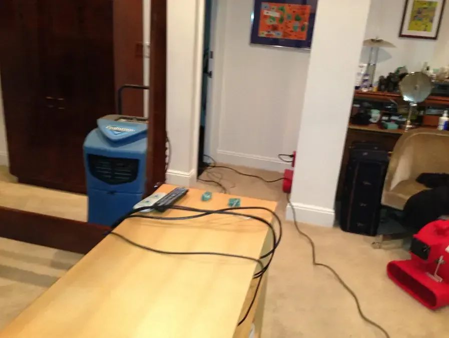 Dehumidifier and air mover drying a water-damaged room in a home