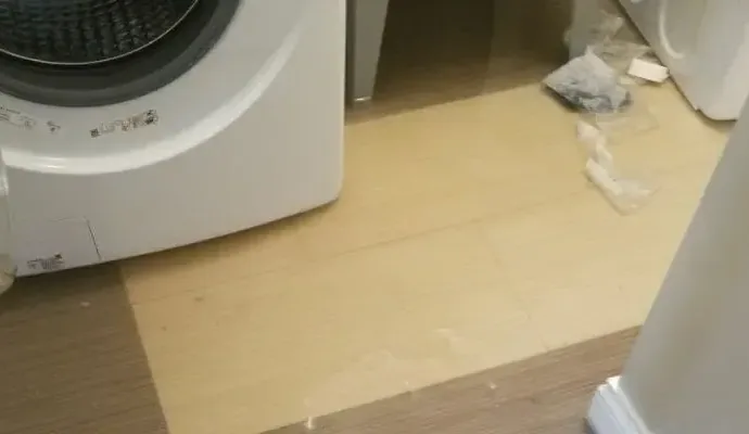 Pooled water and towels beside a front-loading washing machine