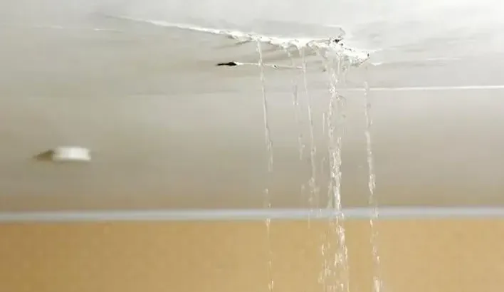 Water streaming through a damaged ceiling into the room below