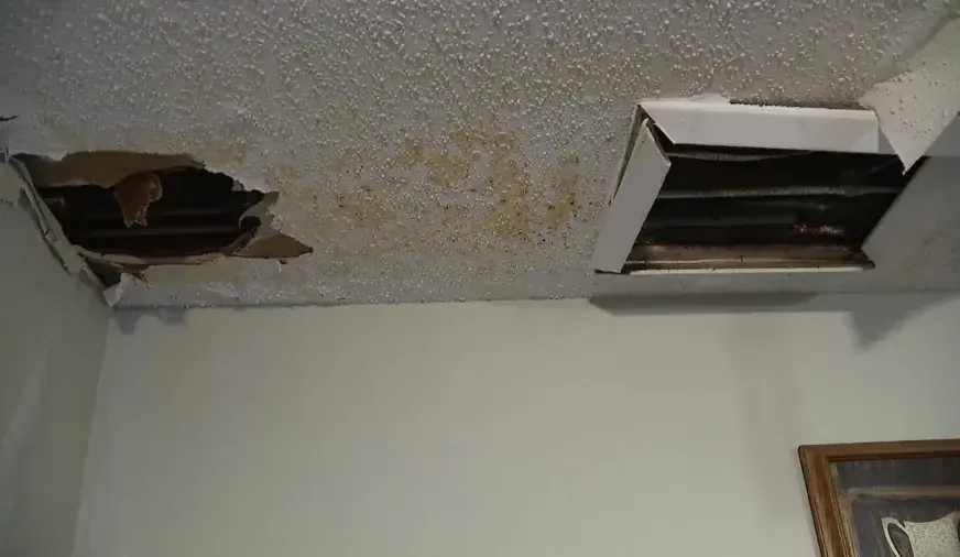 Water-stained ceiling with openings exposing the space above the drywall