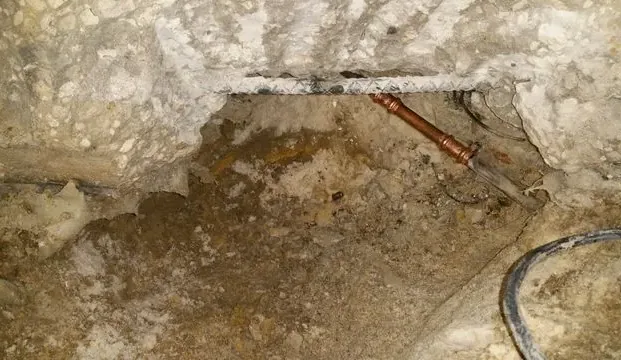 Copper supply pipe exposed inside an opened concrete slab floor